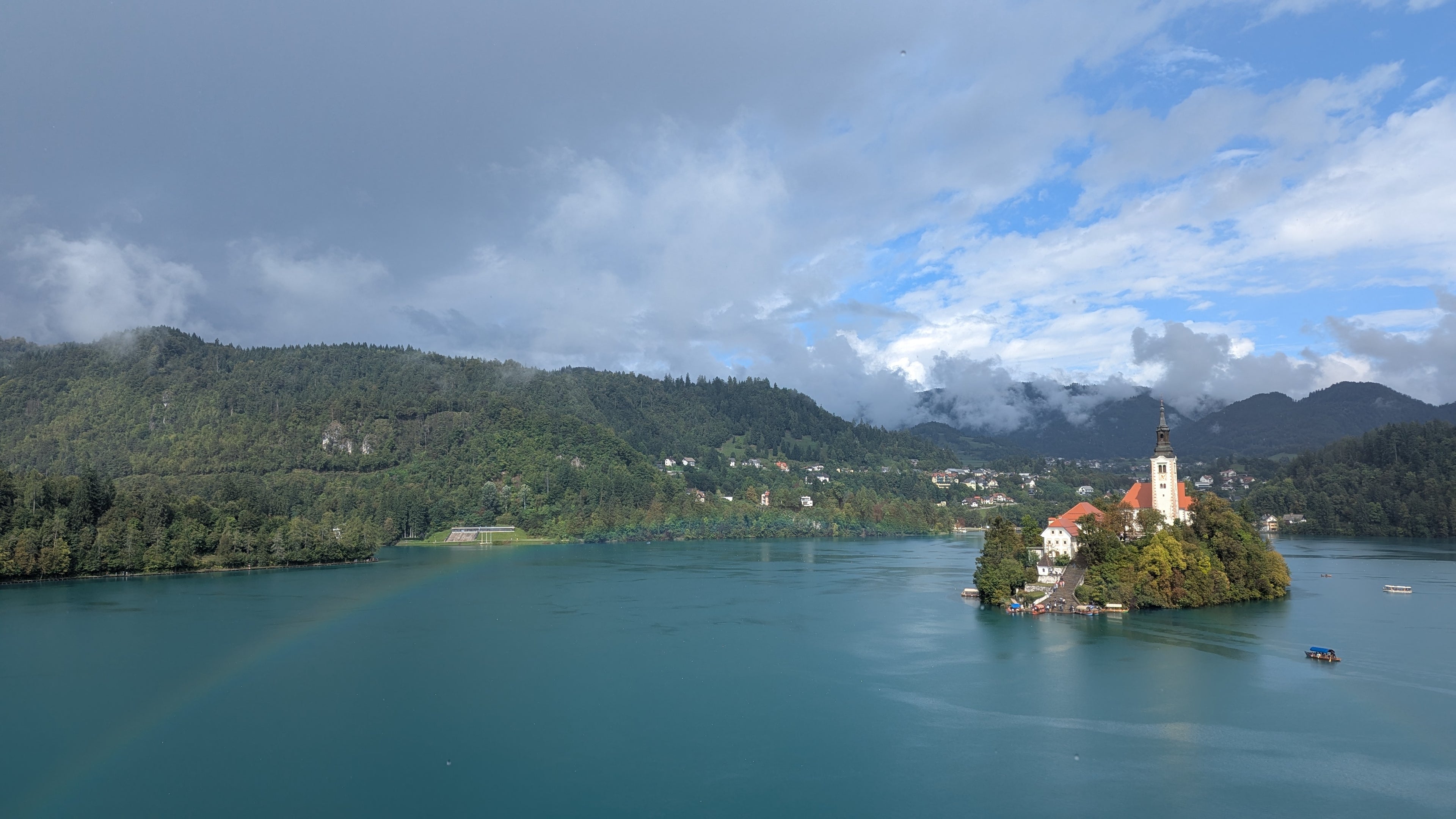 Island with a church in a lake surrounded by mountains under a cloudy sky